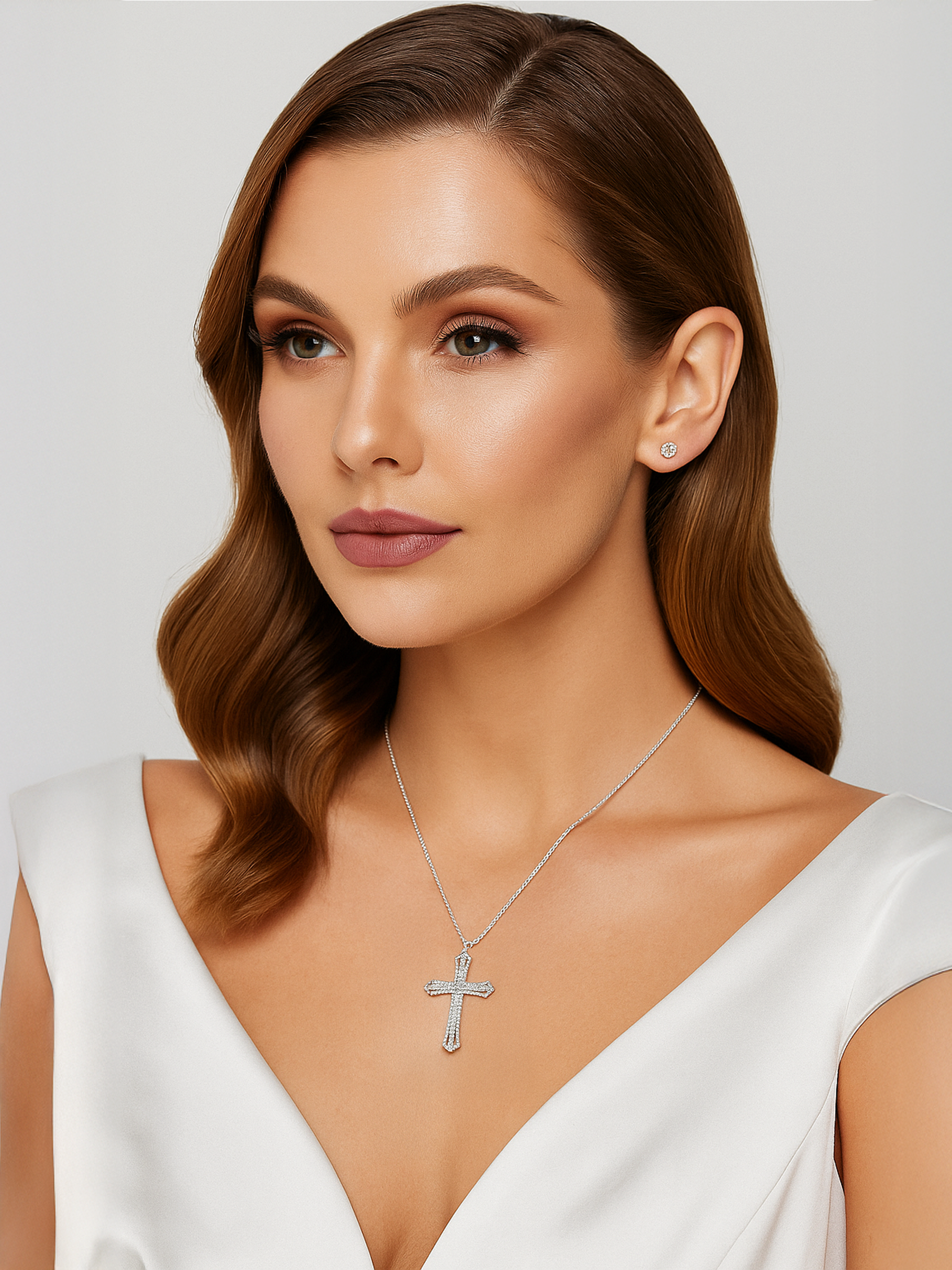Woman wearing a silver cross necklace and earrings