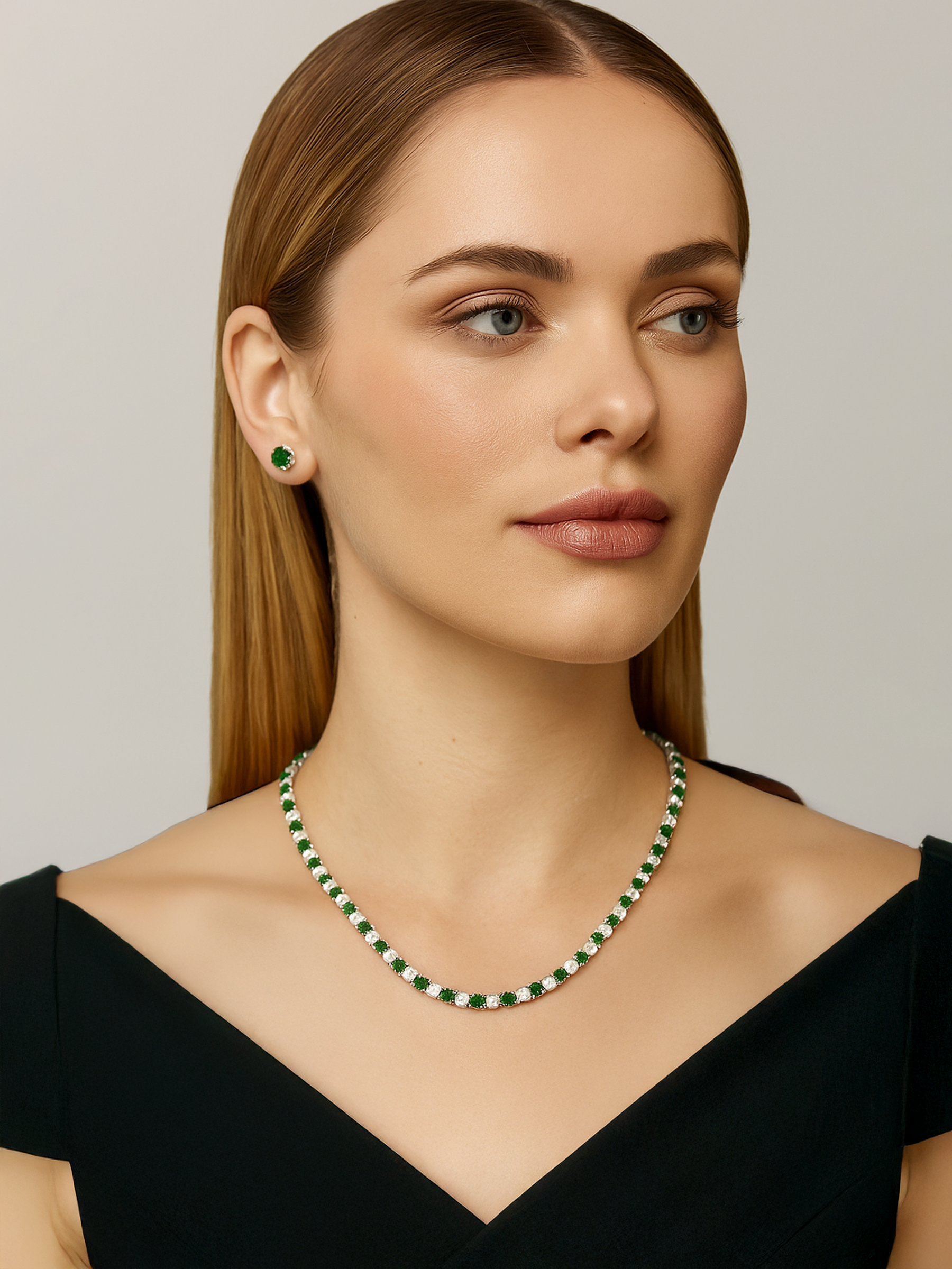 Woman wearing a green and white tennis necklace and earrings 